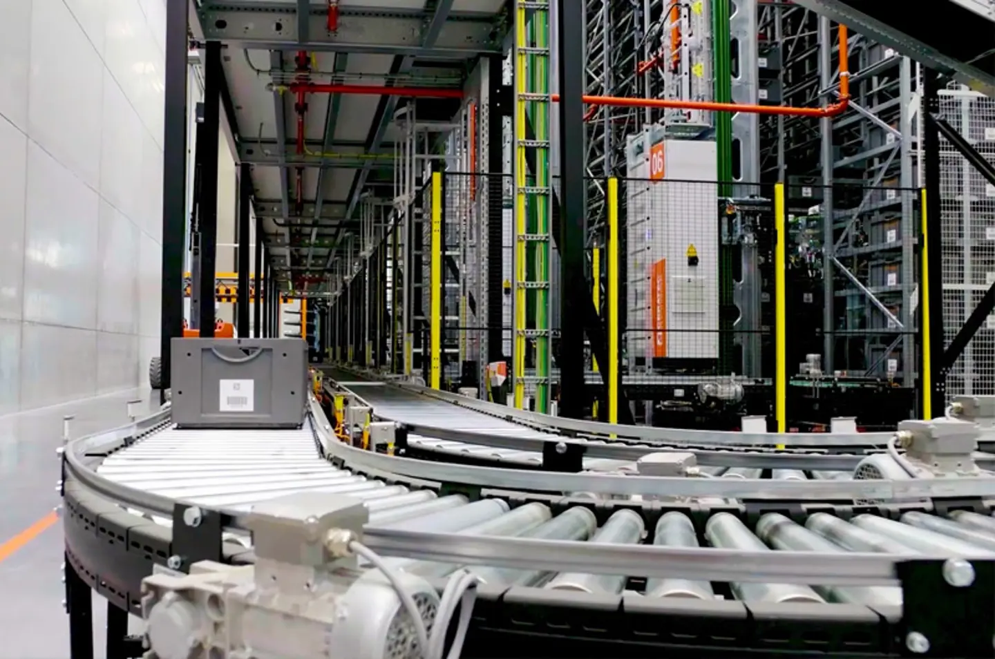 Automatisiertes Lager-Fördersystem mit Rollenbahnen und Schutzzaun für den Materialfluss