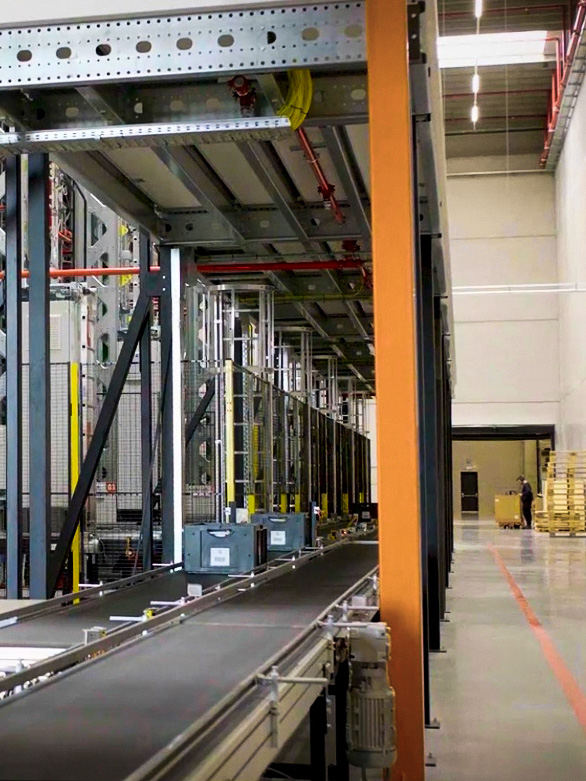 Mitarbeiter überquert den Bereich eines Lager-Fördersystems mit installierten Schutzbarrieren