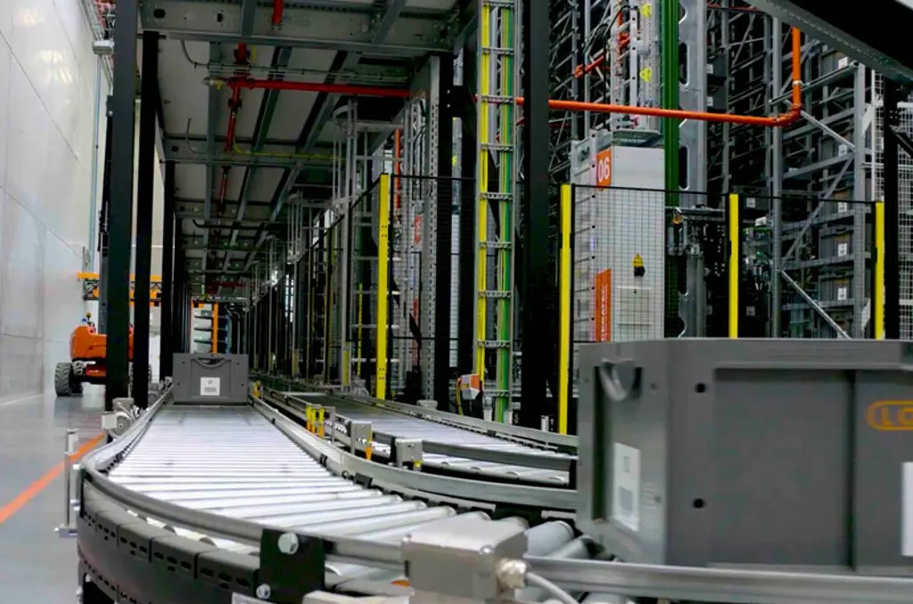 Automatisierte Sortieranlage im Lager mit Förderstrecke und Schutzzaun für sicheren und effizienten Materialfluss