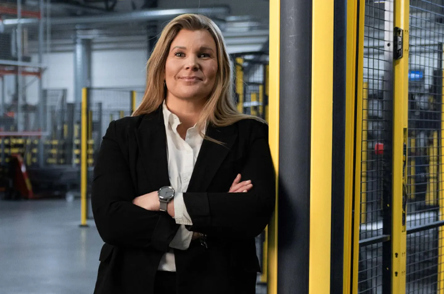 Karin Sanden Ahlqvist, Axelent CEO, lehnt an einem schwarzen und gelben Poller mit  einem industriellem Setting im Hintergrund