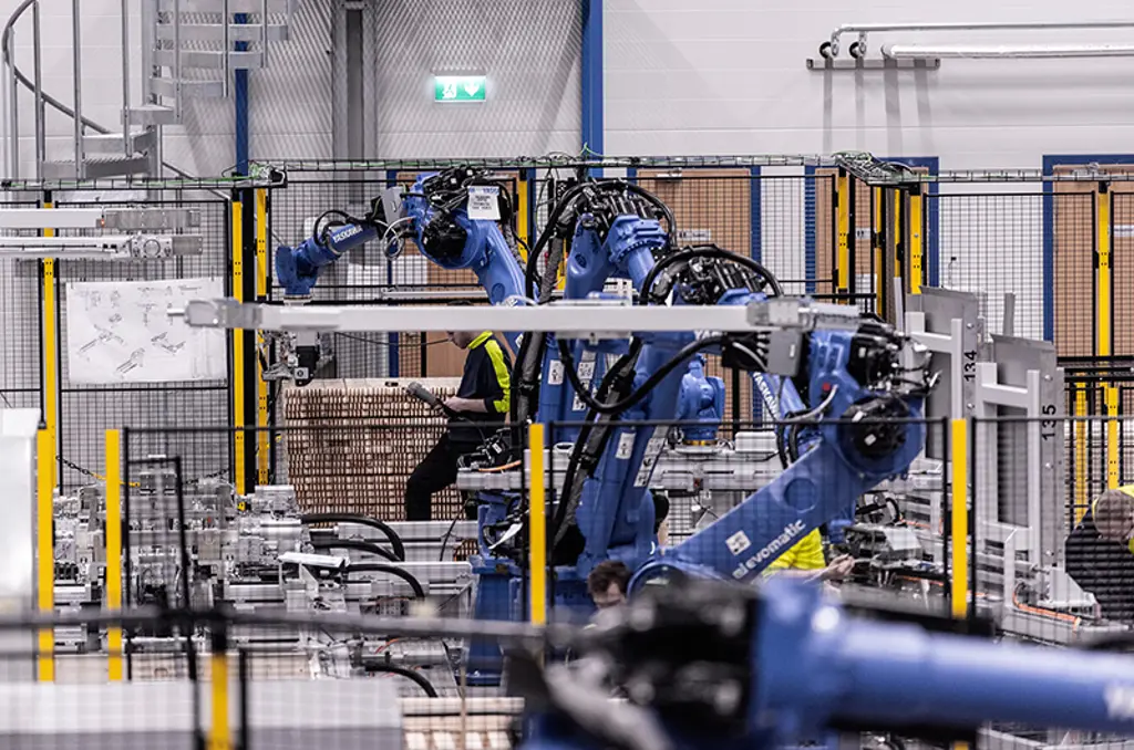Roboterarme palettieren Kartons innerhalb einer gesicherten Automatisierungszelle