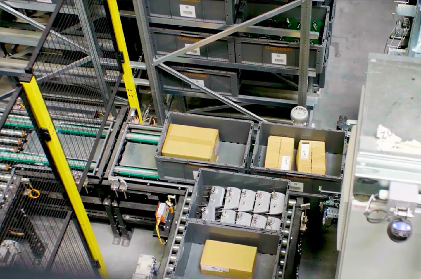 Automatisiertes Materialflusssystem mit Rollenförderern und Behältern für den Transport verpackter Waren