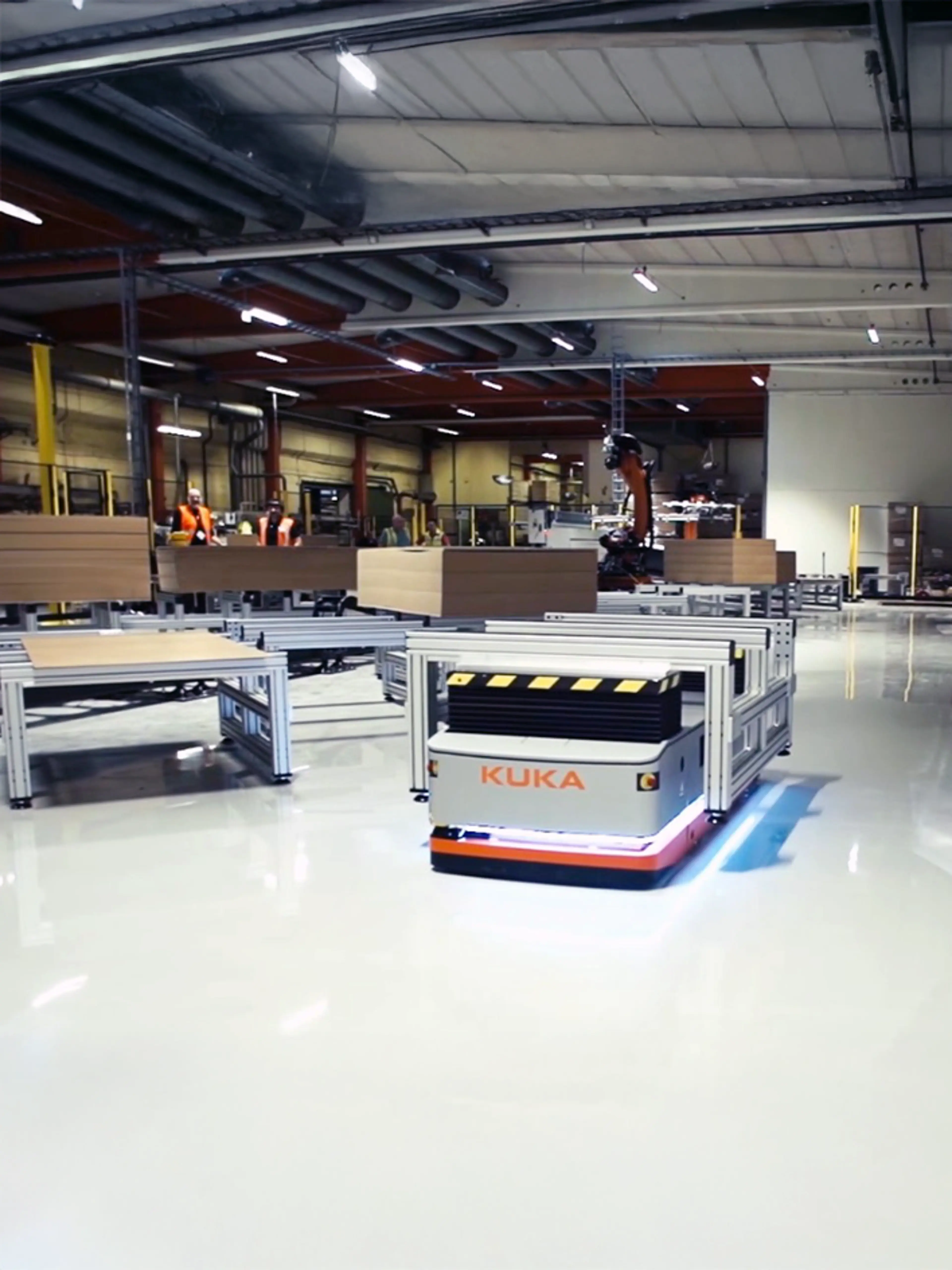 Industrielle mobile Roboter im Lagerbetrieb mit Sicherheitsbarrieren, die Fußgängerbereiche von Roboterwegen trennen.