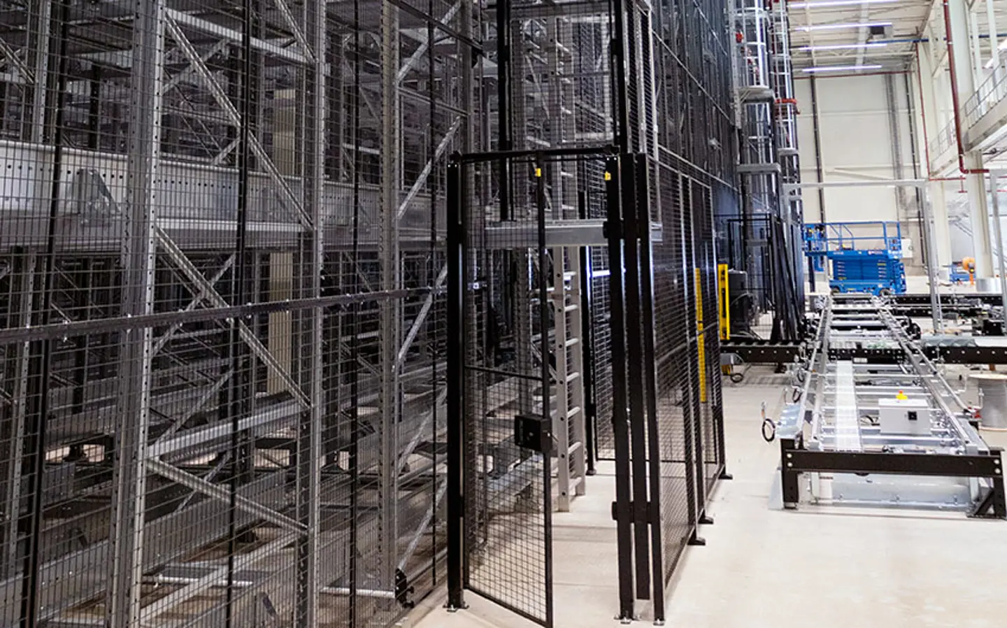 Lager mit hohen Regalen, Schutzzäunen und Fördertechnik